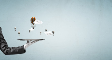 Hand of waitress presenting balloons on tray.