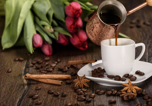 Pouring coffee from a jezvethrough a cup of coffee