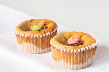 Two delicious, homemade small cheesecakes with melted chocolate and colorful sugar flowers icing. Space for text