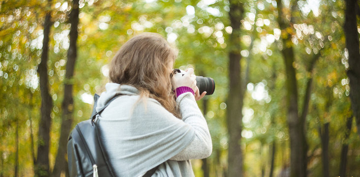 woman with photo camera in autumn forest