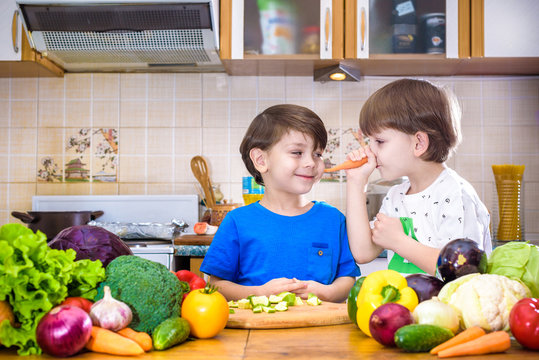 Healthy eating. Happy children prepares and eats vegetable salad in kitchen