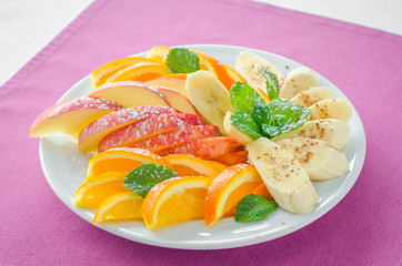 Bananas, apples , pineapple, oranges. Assorted fruits on the plate with pink background. Flat lay. Vegan. Healthy food concept.