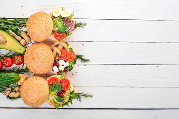 Set Burger, sandwich. with quail eggs, cucumbers and corn, salami and seafood. On a wooden background. Top view. Copy space.