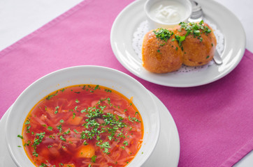 Ukrainian borsch soup and garlic buns on the table. Horizontal view from above.