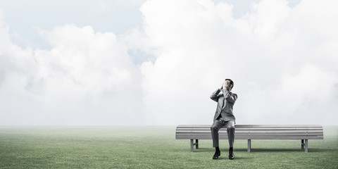 Young man in summer park on bench do not want to see anything