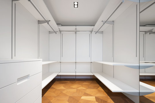 Large white walk-in closet with parquet