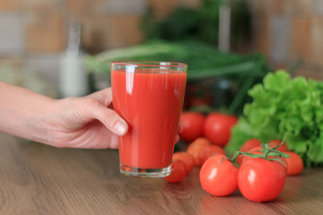 Woman is holding tomato juice on the kitchen