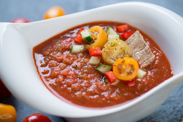Close-up of cold spanish gazpacho soup served in a white bowl, selective focus
