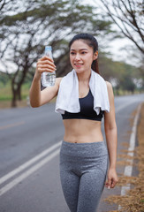 young sporty woman with bottle of water in park