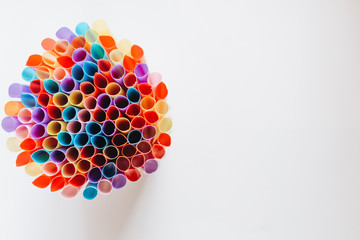 pile of colorful cocktail straws over white background