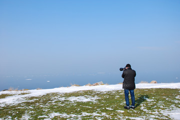 Photographer by a coast with melting snow