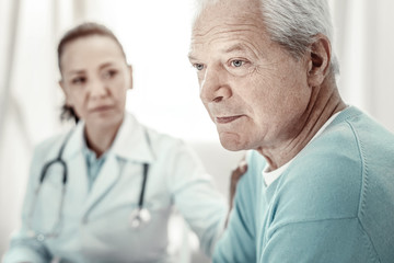 Fototapeta premium Think about it. Agitated serious aged man sitting by the table looking aside and concentrating on his own thoughts.