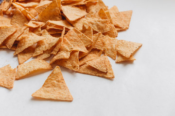 Pile of delicious crispy nachos of out pack on white background, traditional Mexican cuisine