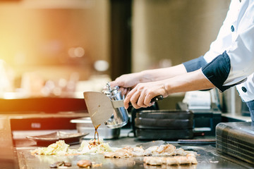 Hand of man take cooking of meat with vegetable grill, Chef cooking wagyu beef in Japanese teppanyaki restaurant