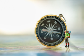 Travel Concept. Traveler miniature figure standing on world map with compass as background.