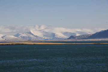 Island landscape with the sea and snow mountains and the blue sky