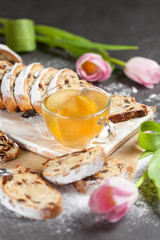 freshly baked cake with sweets, raisins and candied fruits, sprinkled with powdered sugar, a hot drink with apples on a gray table with pink tulips