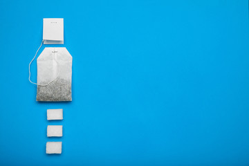 A bag of classic tea with sugar cubes on a blue background, empty space for text.