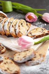 freshly baked cake with sweets, raisins and candied fruits, sprinkled with powdered sugar on a gray table with pink tulips