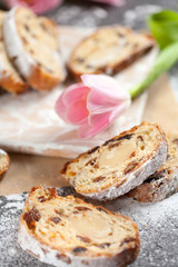 freshly baked cake with sweets, raisins and candied fruits, sprinkled with powdered sugar on a gray table with pink tulips