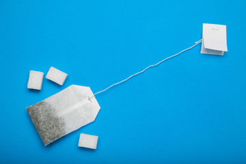 A bag of tea with sugar, a concept on a blue background.