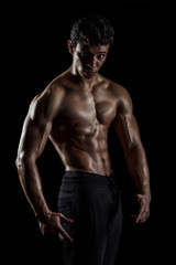 Highly retouched fitness model and bodybuilder, Looking and posing abs and chest. concept of power and strength. black background.