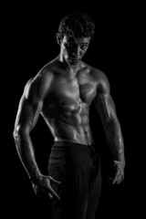 Naklejka na ściany i meble Highly retouched black and white fitness model and bodybuilder, Looking and posing abs and chest. concept of power and strength. black background.