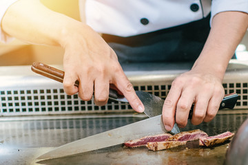 Hand of man take cooking of meat with vegetable grill, Chef cooking wagyu beef in Japanese teppanyaki restaurant