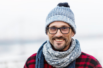 Portrait of smiling urban man in glasses and hat. Happy smiled guy in winter knitted hat and scarf....