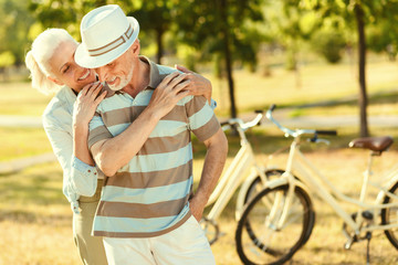 Retired couple. Joyful positive aged man looking at his wife and smiling while enjoying his time together with her