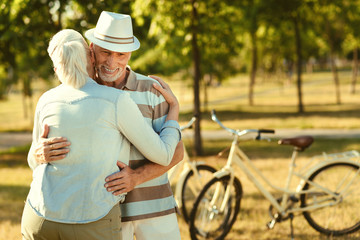 Care and support. Positive nice retired couple standing together and hugging each other while expressing their love