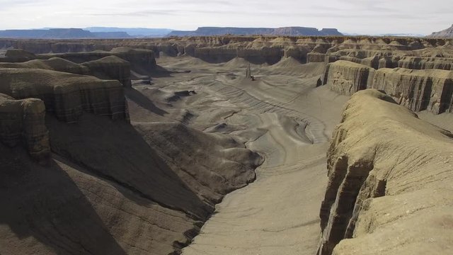 Flying low over desert cliffs towards open valley in the desert near Caineville Utah.