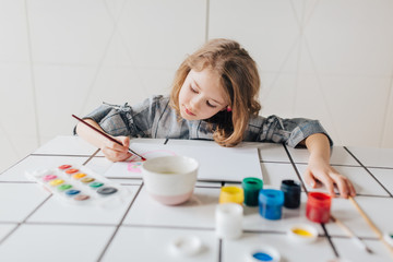 Little girl painting with paintbrush and colorful paints 