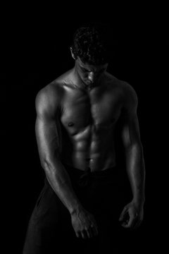 Highly retouched black and white fitness model and bodybuilder, Looking and posing abs and chest.  concept of power, strength and self-confidence. black background.