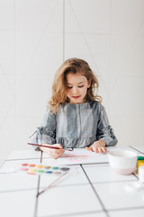 Little girl painting with paintbrush and colorful paints 