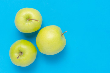 Green apples on a bright, clean, blue background.