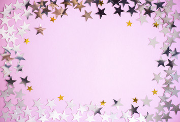 Frame of silver and gold shiny stars on pink background. Decorations concept with copy space for design, display, holiday. Top view