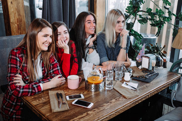 four friends in the cafe look at the camera and laugh