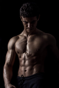 Highly retouched fitness model and bodybuilder, Looking and posing abs and chest. concept of power, strength and self-confidence. black background.