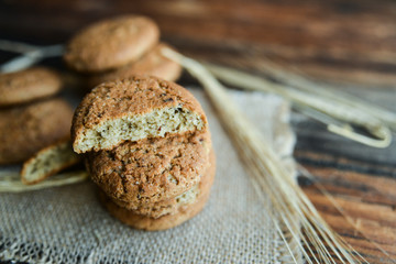 fresh homemade oatmeal cookies on wooden background with spikes of oats