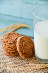 fresh oatmeal cookies with milk on wooden background