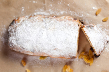 freshly baked cake with sweets, raisins and candied fruits, sprinkled with powdered sugar on a gray table