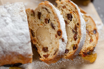 freshly baked cake with sweets, raisins and candied fruits, sprinkled with powdered sugar on a gray table