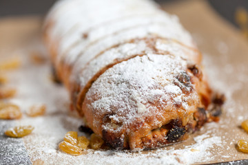 freshly baked cake with sweets, raisins and candied fruits, sprinkled with powdered sugar on a gray table