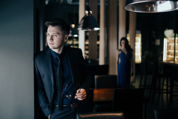 Man is waiting for young woman to meet at restaurant. Concept of being late for meeting, relationship of couple