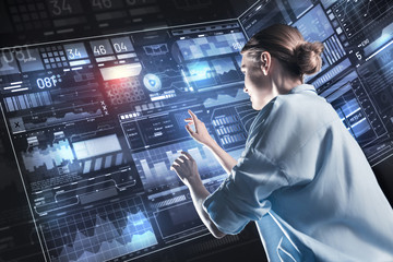 Fototapeta premium Calm employee. Peaceful confident young programmer feeling calm while working with a futuristic device and smiling