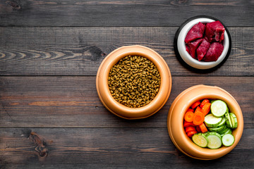 Ingredients for dry pet food. Meat and vegetables zucchini and carrot on dark wooden backgroud top view copy space