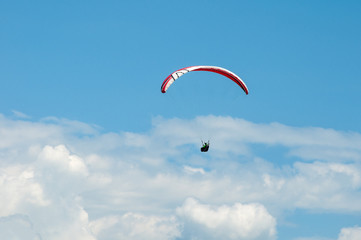 Paraglider flying in the blue sky against the background of clouds. Paragliding in the sky on a sunny day.