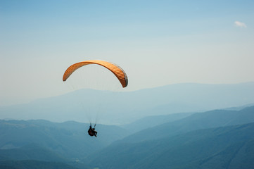 Paraglider flies over a mountain valley on a sunny summer day. Paragliding in the Carpathians in...
