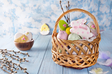 Easter cookies, bunnies and Multicolored Easter eggs in a basket on light blue background